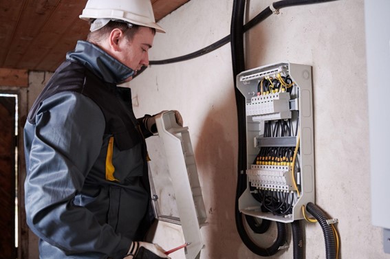 Instalações elétricas: 3 maneiras de manter seu empreendimento seguro | Imagem de um homem mexendo em um painel de eletricidade