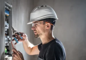 man electrical technician working switchboard with fuses installation connection electrical equipment min 980x679 1